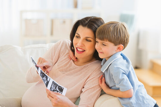 Pregnant woman with son (4-5) looking at ultrasound photo