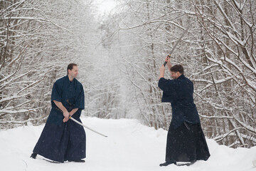 Duel of two samurai warriors on an empty road in a winter forest