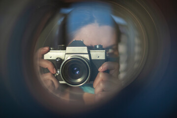 The photographer takes pictures with a retro camera. A look through the lens concept - 410279828