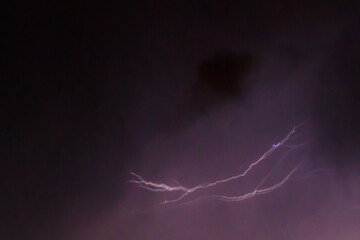 Lightning discharges in the stormy sky under dark rain clouds at night