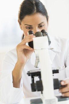 Female scientist looking through microscope