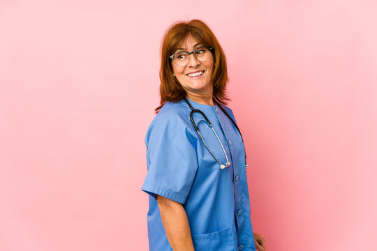 Middle age caucasian nurse woman isolated looks aside smiling, cheerful and pleasant.