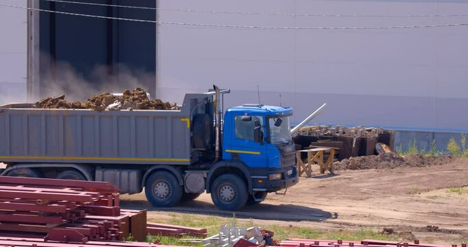 Excavation at a construction site, a blue multi-axle truck loaded with earth drives along the dusty road of a construction site to unload 