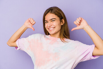 Young skinny caucasian girl teenager on purple background feels proud and self confident, example...