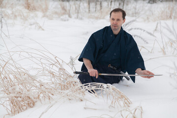 samurai warrior meditates with a sword in the middle of an empty winter field