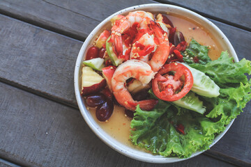 Spicy Thai fruit salad with Shrimps on wooden table at cafe , Thai spicy style healthy food Thai cuisine.