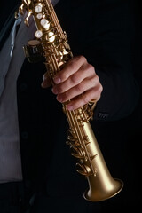 soprano saxophone in the hands of a guy on a black background