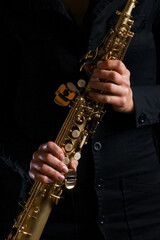 soprano saxophone in the hands of a girl on a black background