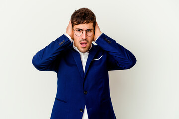 Young business caucasian man isolated on white background covering ears with hands trying not to hear too loud sound.