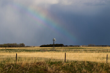 Nature Rainbow over pretty green Nebraska landscape with windmill. High quality photo