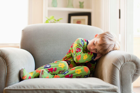 Boy in his pijamas sleeping on armchair