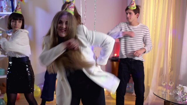 Portrait of positive plus-size woman dancing with friends at background. Happy carefree Caucasian lady having fun with guests at birthday party looking at camera. Celebration and leisure.
