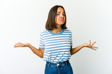 Young mixed race woman doubting and shrugging shoulders in questioning gesture.