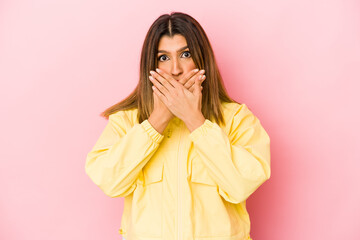 Young indian woman isolated on pink background shocked covering mouth with hands.