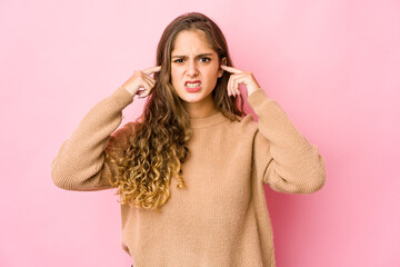 Young caucasian woman covering ears with fingers, stressed and desperate by a loudly ambient.