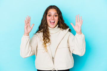 Young caucasian curly hair woman isolated receiving a pleasant surprise, excited and raising hands.
