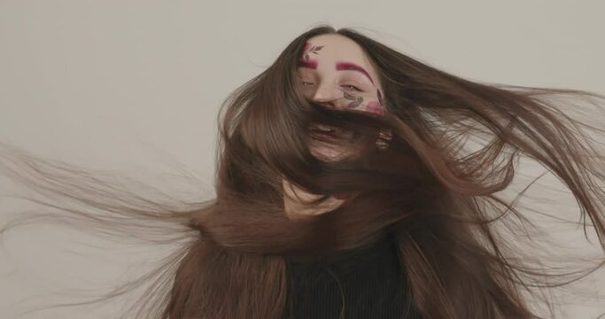 beautiful long hair girl develops under a stream of air during photography in the studio