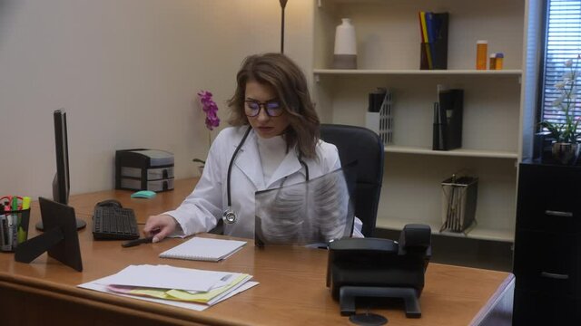 Angry doctor knocks all papers off her desk out of frustration from results of chest x-ray