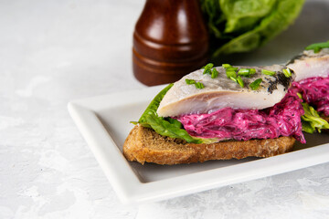 Close up of herring sandwich with beet and green salad on wooden board. Herring is a saurce of omega 3 fats healthy for brain and mental clarity. Brain food concept. Home cooking