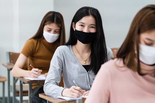 Group Of College Students Wearing A Face Mask And Keep Distance While Studying In The Classroom And College Or University Campus To Prevent COVID-19 Pandemic. The New College Or University Campus Life