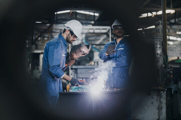 Industrial Worker at the factory welding. Workers wearing industrial uniforms and Welded Iron Mask at factory welding plants