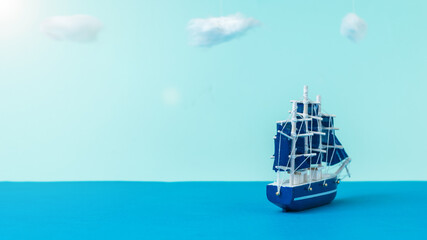 A sailboat with blue sails sailing away from the shore. Installation.