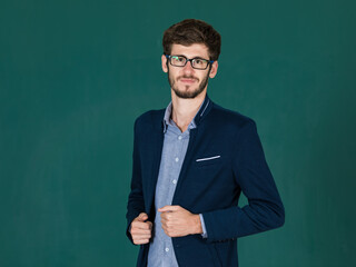 Studio shot portrait of a cute and elegant executive man wearing eyesglasses in blue suit jacket standing and smile to the camera with self-confident on green screen