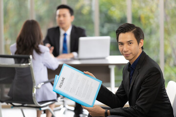 Young Asian male employee holding a resume waits for a job interview with the human resource manager.