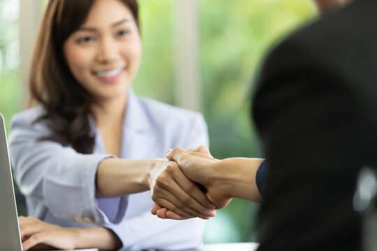 Photo of handshaking in a personnel office after job interview with soft focus on Asian young applicant woman. Concept of career application and congratulation