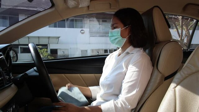 Asian woman hand using alcohol spray to disinfect steering wheel and using wipes in the car. protection against the coronavirus or Covid-19.