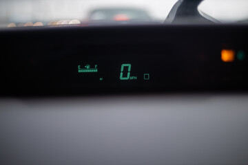 Digital speedometer shining on dashboard under a wet windshield