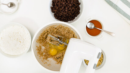 Chocolate Chip Cookies recipe. Mix of butter, sugar and eggs in a bowl, close up on white background, view from above