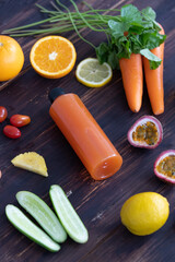 bottle of cold-pressed healthy juice from various ingredients of fruits and vegetables on rustic wooden background with copy space from top view. Detox and diet food and drinks concept