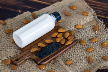 Top view of almond milk with sesame in a plastic bottle with almonds nut and sesame seeds on rustic fabric wooden tray and table. Concept of organic healthy detox and diet food and drinks.