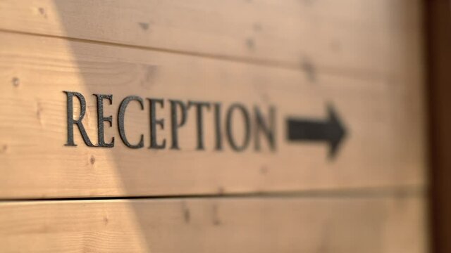 Reception direction sign with arrow in mountian hotel on wooden board