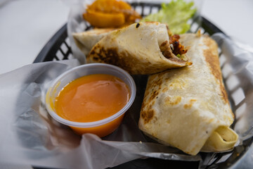 Spicy pork burritos and lettuce in a plastic basket