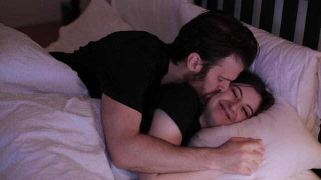 Happy young couple cuddling and kissing in in bed. HD 24FPS.