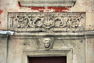 Elements of the architectural decor of the building. A fragment of the wall of an old stone house with peeling plaster.
