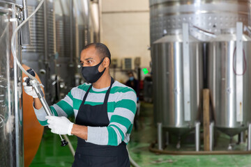 Winery worker checks the pressure in a steel barrel