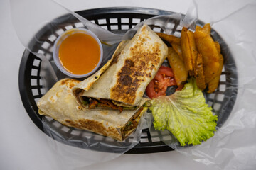 Spicy pork burritos and lettuce in a plastic basket