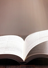 Fototapeta premium A Bible Open on a Rustic Wooden Table with Pages Blowing Open