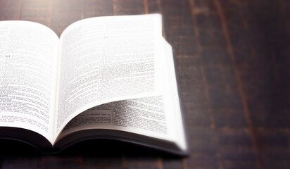Obraz premium A Bible Open on a Rustic Wooden Table with Pages Blowing Open