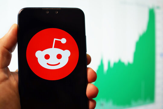 Reddit application icon on a phone screen against stock index screen background. Reddit is an American social news aggregation, web content rating, and discussion site. PENANG, MALAYSIA - FEB 2, 2021.