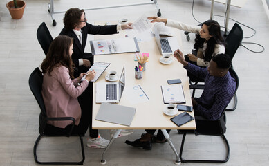 African American and caucasian four people Sitting in a meeting about the proposed business plans in the new quarter. at the meeting room in the office have coffee and computers.