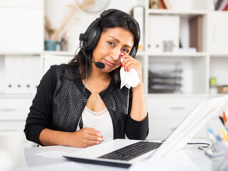 Portrait of frustrated tearful Hispanic woman customer support phone operator at workplace