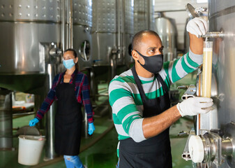 Winemaker in protective masks analyze the white wine in a beaker