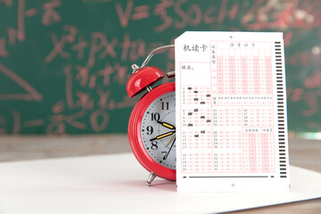 Alarm clock and answer card in front of blackboard