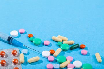 Close-up colorful scattered tablets, blister with red medical pills, syringe