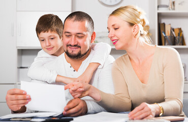 Happy friendly family of three with papers at home