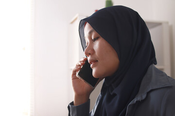 Happy Asian muslim woman wearing hijab talking on phone, good news conversation communication concept, smiling expression